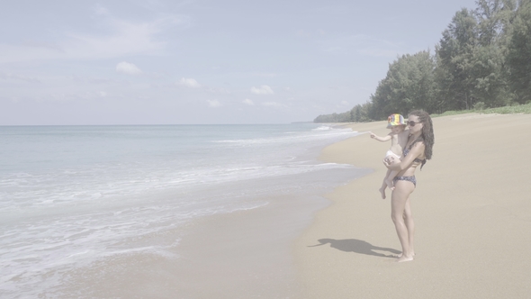 Mom and Baby Are Walking Along the Shore