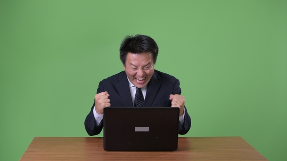 Mature Japanese Businessman Against Green Background