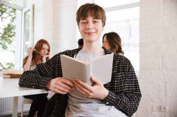 Smiling young guy reading book - Stock Photo - Images