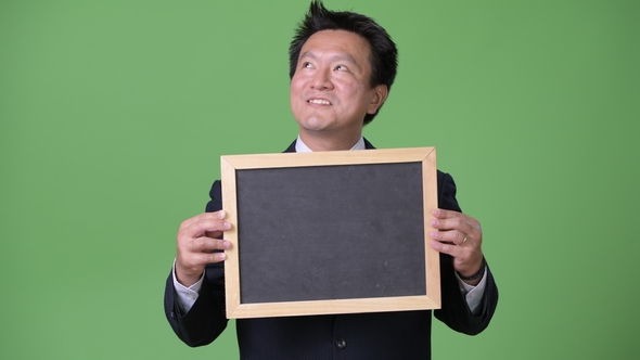 Mature Japanese Businessman Against Green Background