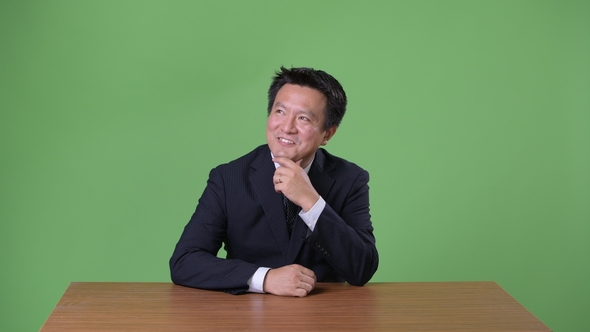 Mature Japanese Businessman Against Green Background alt