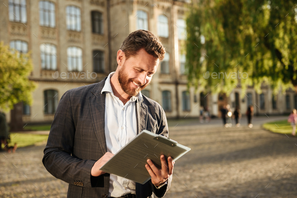 Image of successful businessman 40s holding clipboard and examin - Stock Photo - Images