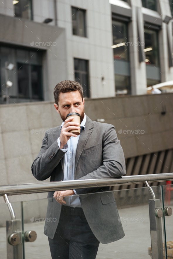 Photo of successful business man 40s in gray suit looking aside, - Stock Photo - Images
