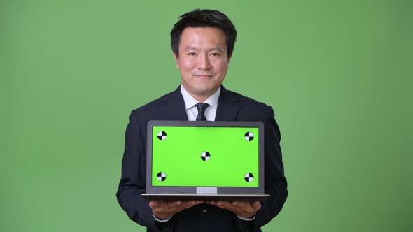 Mature Japanese Businessman Against Green Background