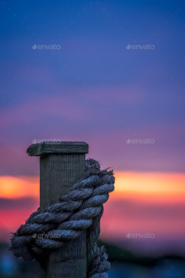 Thick rope tied around a wooden fence - Stock Photo - Images