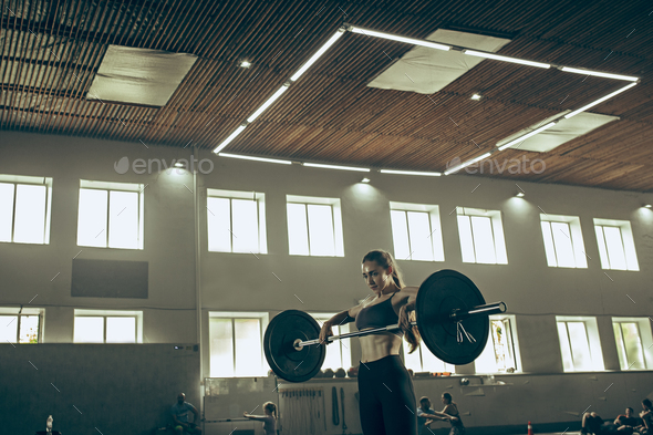 Fit young woman lifting barbells working out in a gym - Stock Photo - Images