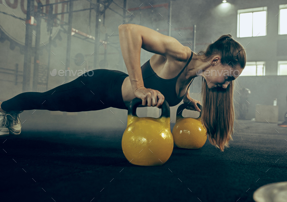 Fit young woman lifting barbells working out in a gym - Stock Photo - Images