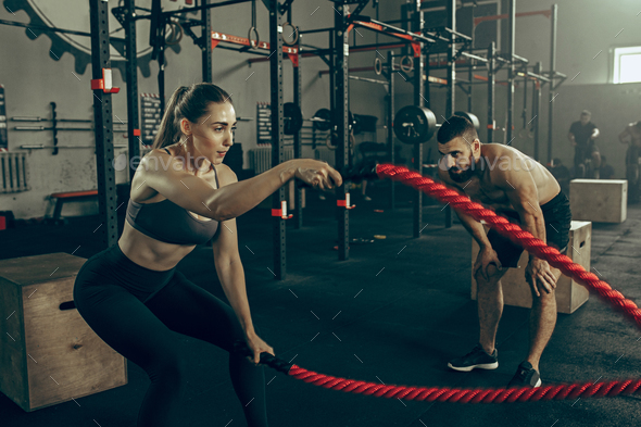 Woman with battle ropes exercise in the fitness gym. Stock Photo by  master1305