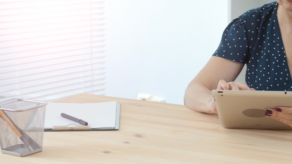 Middle-aged Woman in Office Working on Digital Tablet alt
