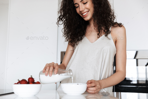 Photo of happy curly woman wearing silk leisure clothing smiling - Stock Photo - Images