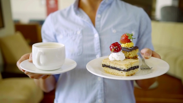 Shot of a Woman Holding Two Plates with Dessert and Cup of Coffee for Breakfast alt