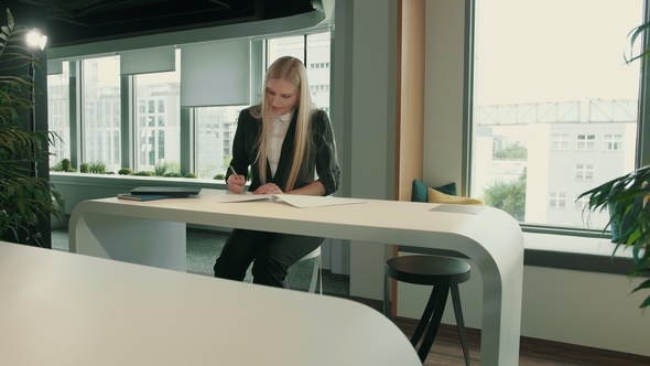 Elegant Woman Working in Stylish Office. Modern Blond Woman in Trendy Suit Sitting at Table in Light alt
