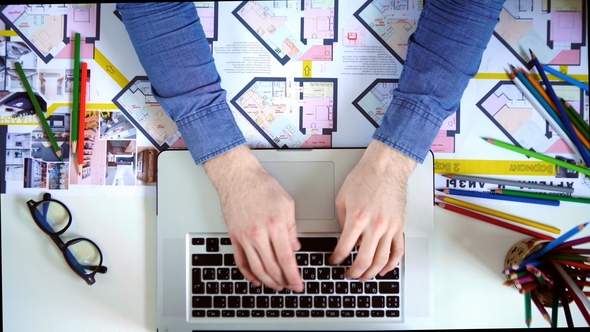 Top View of Desk with Office Supplies. Man Typing on His Laptop alt