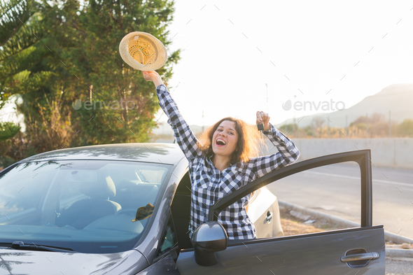 Happy woman driver showing car keys and leaning on car door Stock Photo by Satura_