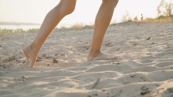 Legs of a Girl Walking Along a Sandy Beach at Sunset
