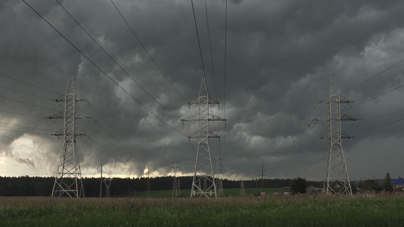 Dark Clouds Float Across Sky Against Electric Power Pylons of Transmission Line