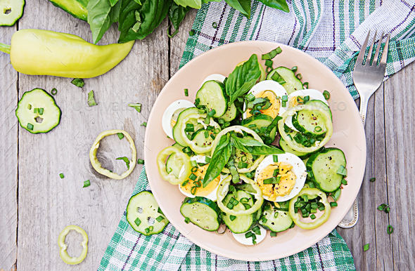 Breakfast in the summer garden. Salad of eggs and cucumbers with green onions and basil. Stock Photo by Timolina