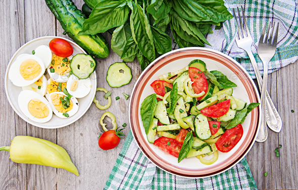 Breakfast in the summer garden. Salad of eggs and cucumbers with green onions and basil. Stock Photo by Timolina