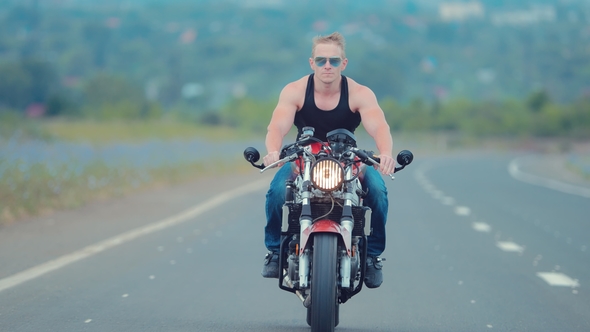 Front View Of A Young Man In Sunglasses Riding A Motorcycle On An