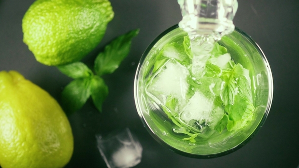 Water From a Bottle in a Glass of Mint and Ice Top View