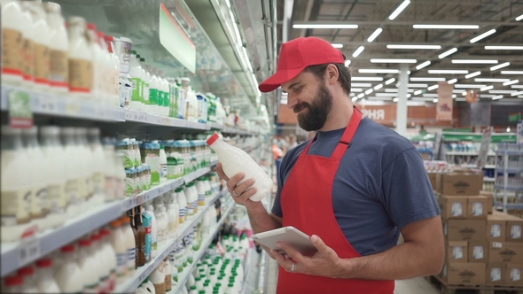 Handsome Male Merchandiser Checking Milk Products with Digital Tablet