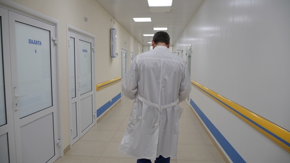 The Doctor Walks Down the Hospital Corridor From the Camera alt