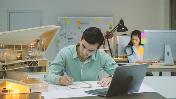 Male Architect Working on an Architectural Model in the Office at Night