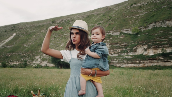 Young Pretty Mother Playing with Her Child in the Middle of Landscape, Smiling alt