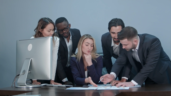 Group of Multiethnic Diverse Young Business People in a Meeting Standing Around a Table with Serious alt