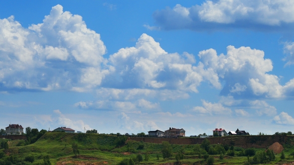 Green Hill with Houses and Cloudy Sky