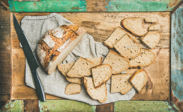 Flat-lay of sourdough wheat bread cut in slices in tray - Stock Photo - Images