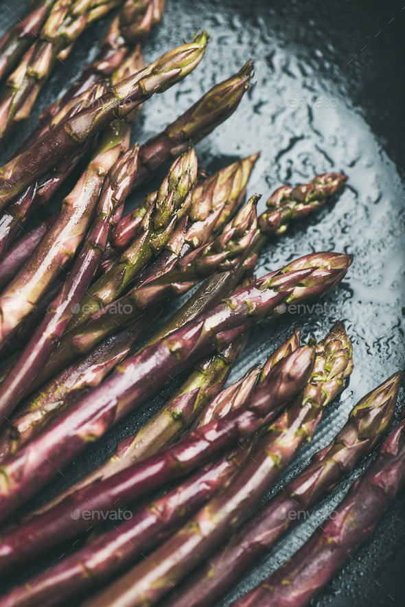 Fresh raw uncooked purple asparagus over dark background - Stock Photo - Images