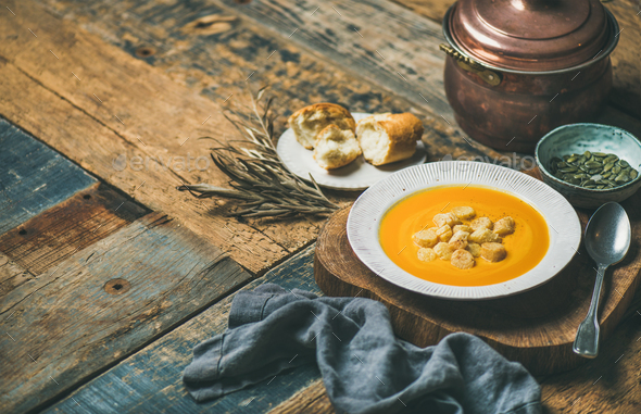 Warming pumpkin cream soup with croutons and seeds, wooden background - Stock Photo - Images