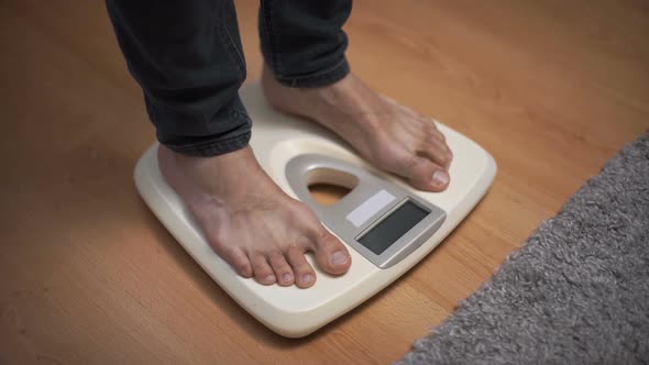 Male Weighting on Floor Scales in Domestic Room, Close Up Feet View