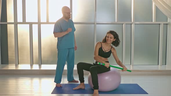 A Physical Therapist Safely Trains a Patient Using Medical Exercise Equipment alt