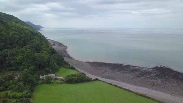 Rotating wide aerial looking west along the forest-like coast of Exmoor. Large sea, and amazing clif alt