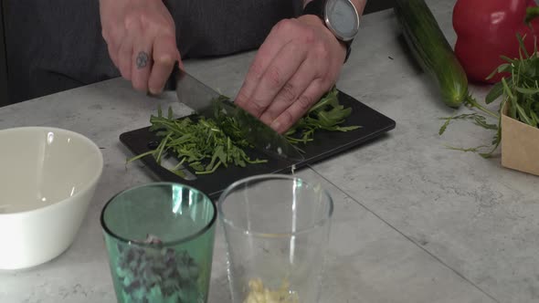 Fresh arugula chopped on small cutting board, other ingredients nearby alt