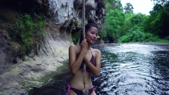 Cute Smiling Asian Girl in Bikini in the River By a Rope Thailand