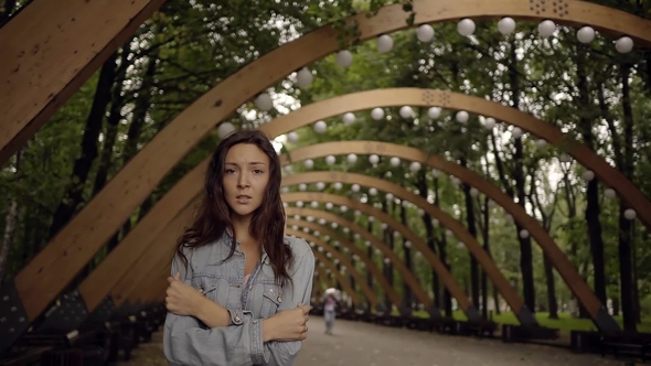 Lonely and Frightened Young Woman Is Standing in Summer Park in Evening alt