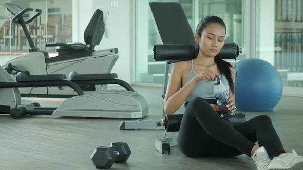 Asian Woman in Gym Drink Water After Exercise