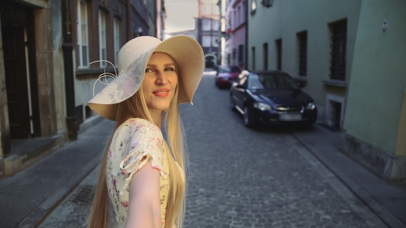 Woman Gesturing Follow Me on Street Smiling Young Woman Looking at Camera and Gesturing Follow Me alt