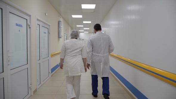 Doctor and Nurse Are Walking Back Along the Corridor of the Hospital alt