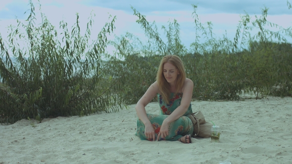 Cheerful Smiling Woman Drawing on Sand at Seaside alt