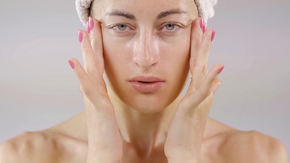 Beautiful Attractive Young Woman Is Applying Brand New a Lotion on Her Face Isolated on Beige alt