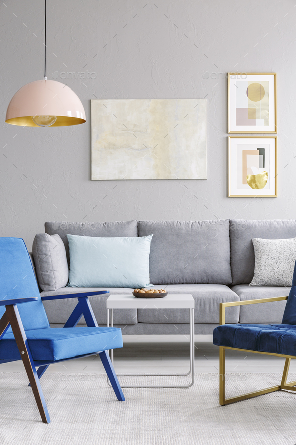 Real photo of two blue chairs standing in front of a grey couch - Stock Photo - Images