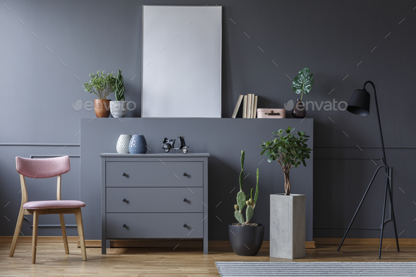 Grey cabinet between wooden chair and plants in living room inte Stock Photo by bialasiewicz
