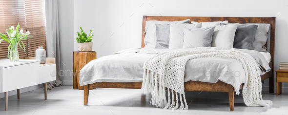 Wooden framed comfortable bed with many pillows, blanket and she - Stock Photo - Images