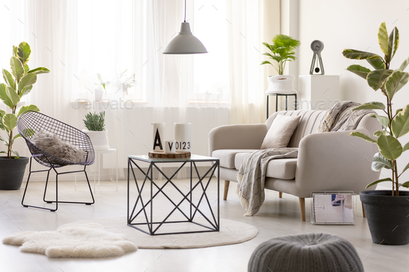 Real photo of a black table standing next to a beige sofa and an - Stock Photo - Images