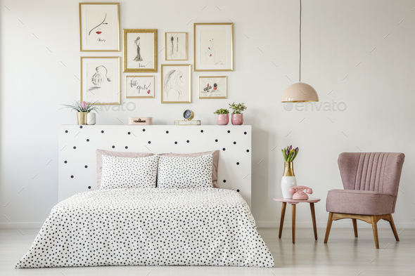 Dotted, double bed, paintings with gold frames and pink armchair Stock Photo by bialasiewicz