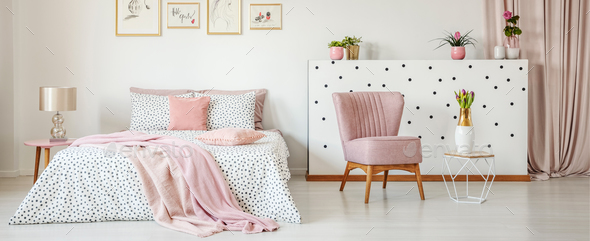 Dotted bedding on double bed placed in white room interior with Stock Photo by bialasiewicz